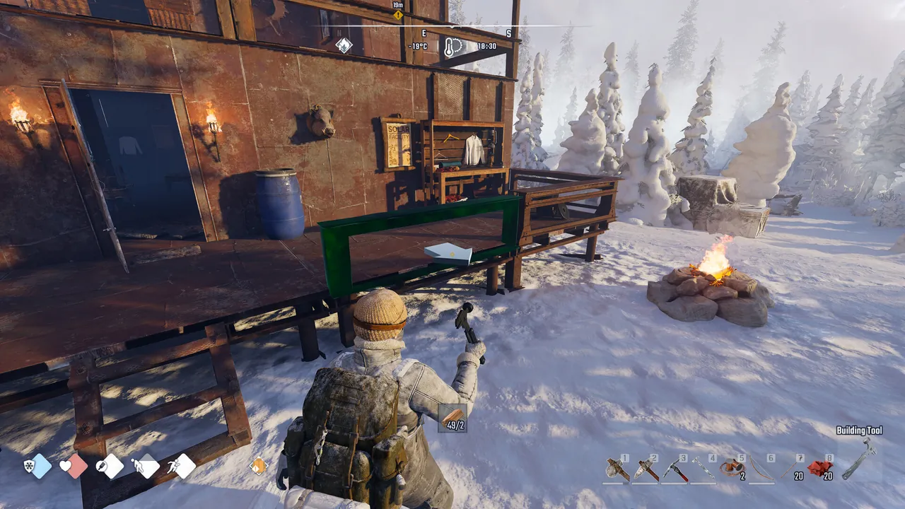 A survivor using the Building Tool to place a frame next to a cabin and a campfire in the snow